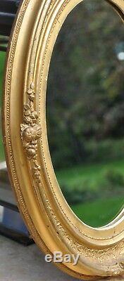 French Antique Louis XVI oval gilt frame mirror, gold leaf on carved wood